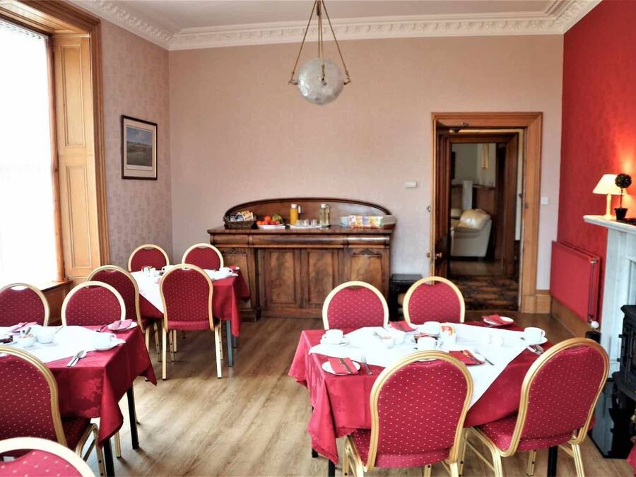 A dining room with round tables and chairs, a wooden counter with food items, and a fireplace.