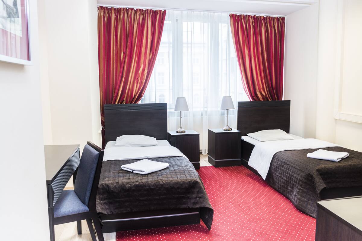Una habitación de hotel con dos camas individuales, un escritorio y una silla.