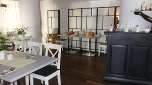 A dining area with white chairs, a table set with plates and cutlery, and a dark wooden floor. - Centrum Scsk Zurawia (Warsaw)
