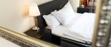A hotel room with a neatly made bed, a bedside lamp, and a nightstand.