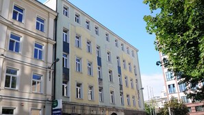 A multi-story building with a central entrance, large windows, and a sign indicating a partnership with sage. - Centrum Scsk Zurawia (Warsaw)