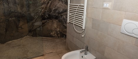 A bathroom with a bidet, a towel rack, and a shower area with a glass door.