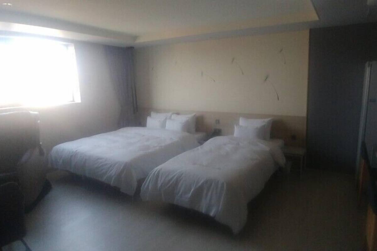A hotel room with two beds, a desk, and a chair.
