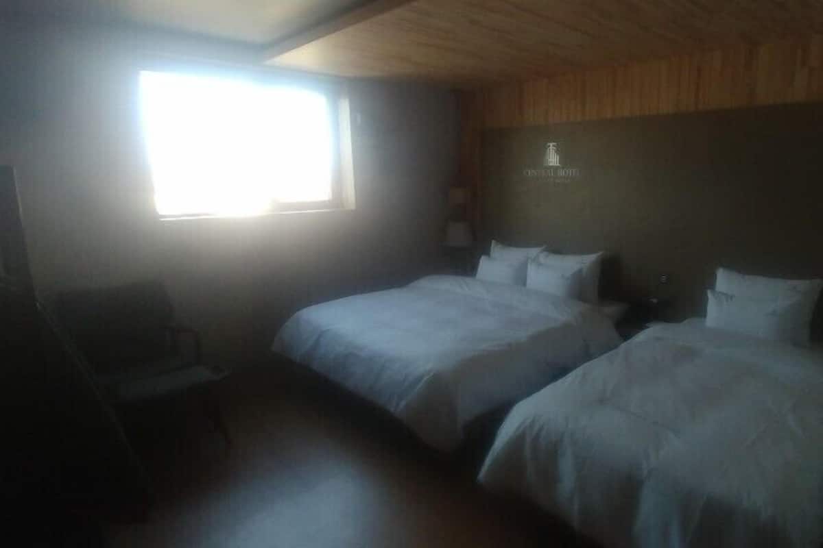 A room with two beds, a window, and a chair.