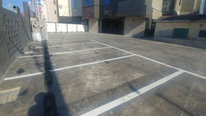 Un espace de stationnement avec des places délimitées et une entrée fermée par une barrière.