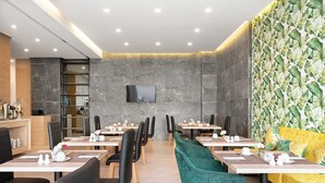 Un restaurant au décor moderne, avec des murs en marbre, un téléviseur à écran plat et différents types de sièges, notamment des tables et des chaises.