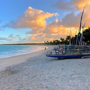 A beach with boats parked on the sand, a clear sky, and palm trees in the background. - Pousada Coco Beach (Ipojuca)