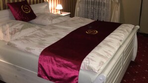 Une chambre d’hôtel avec un lit, une table de chevet, une lampe, une télévision et une fenêtre avec des rideaux.