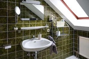 A bathroom with a skylight, a sink, a mirror, and a towel rack.
