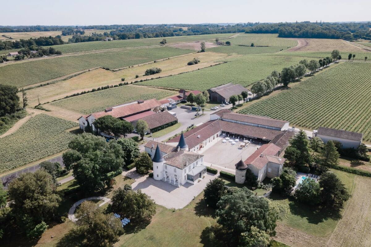 An aerial view of a large estate with multiple buildings, expansive fields, and a central courtyard.