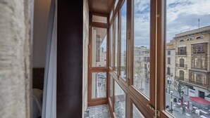 Blick aus einem Fenster mit Holzrahmen auf die darunterliegende Straße.