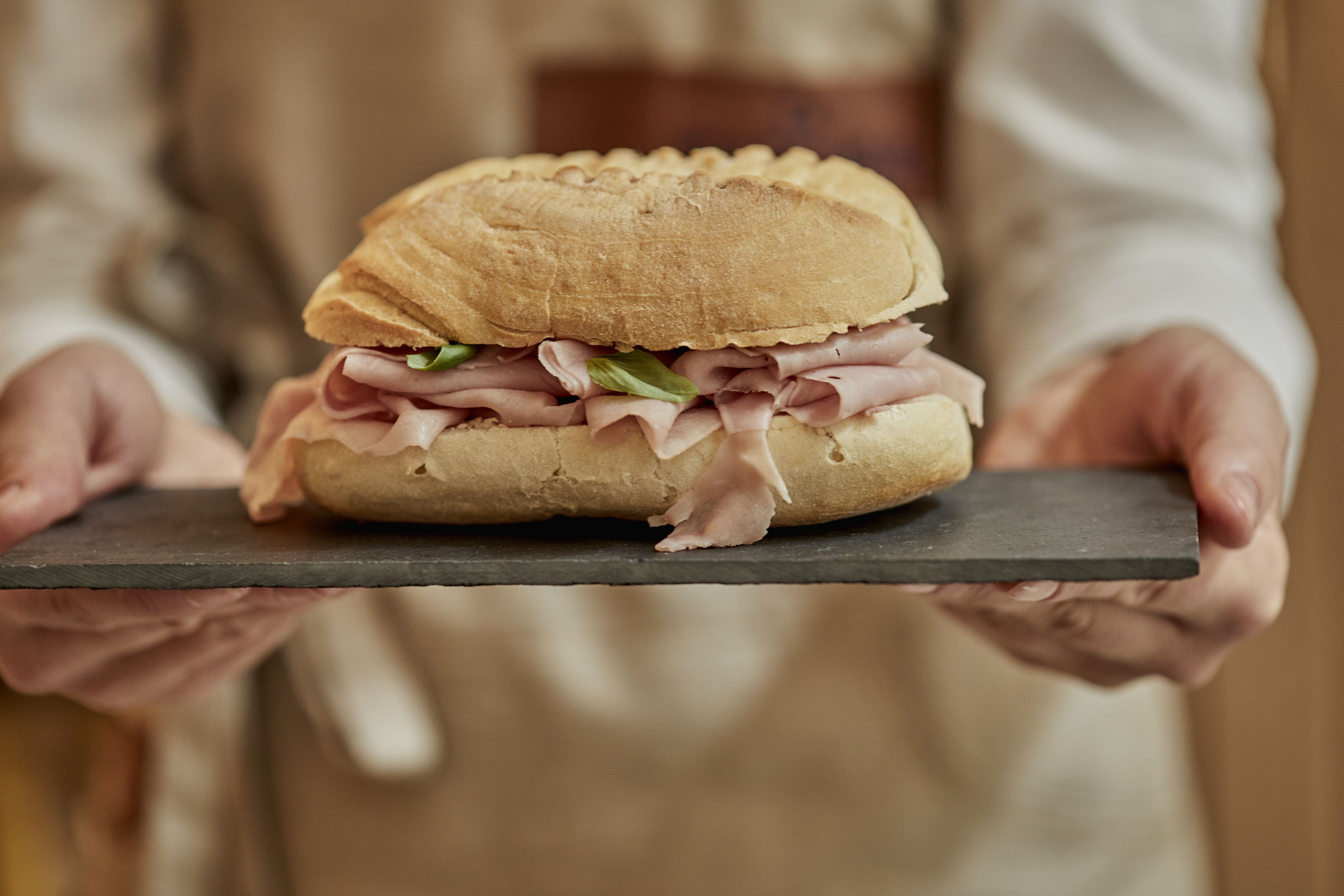 A person holding a sandwich on a slate board.