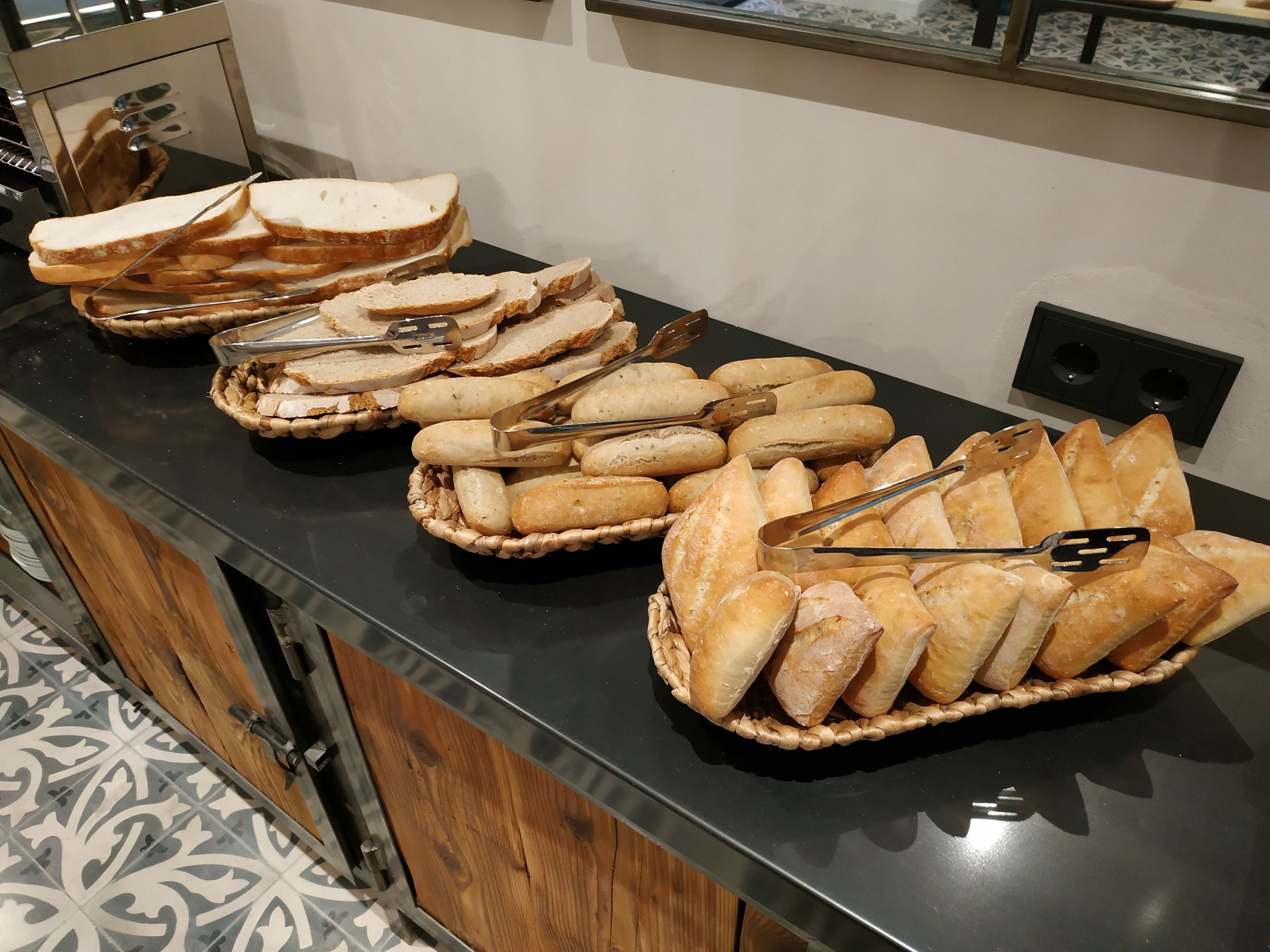 A buffet counter with various bread and pastry options.