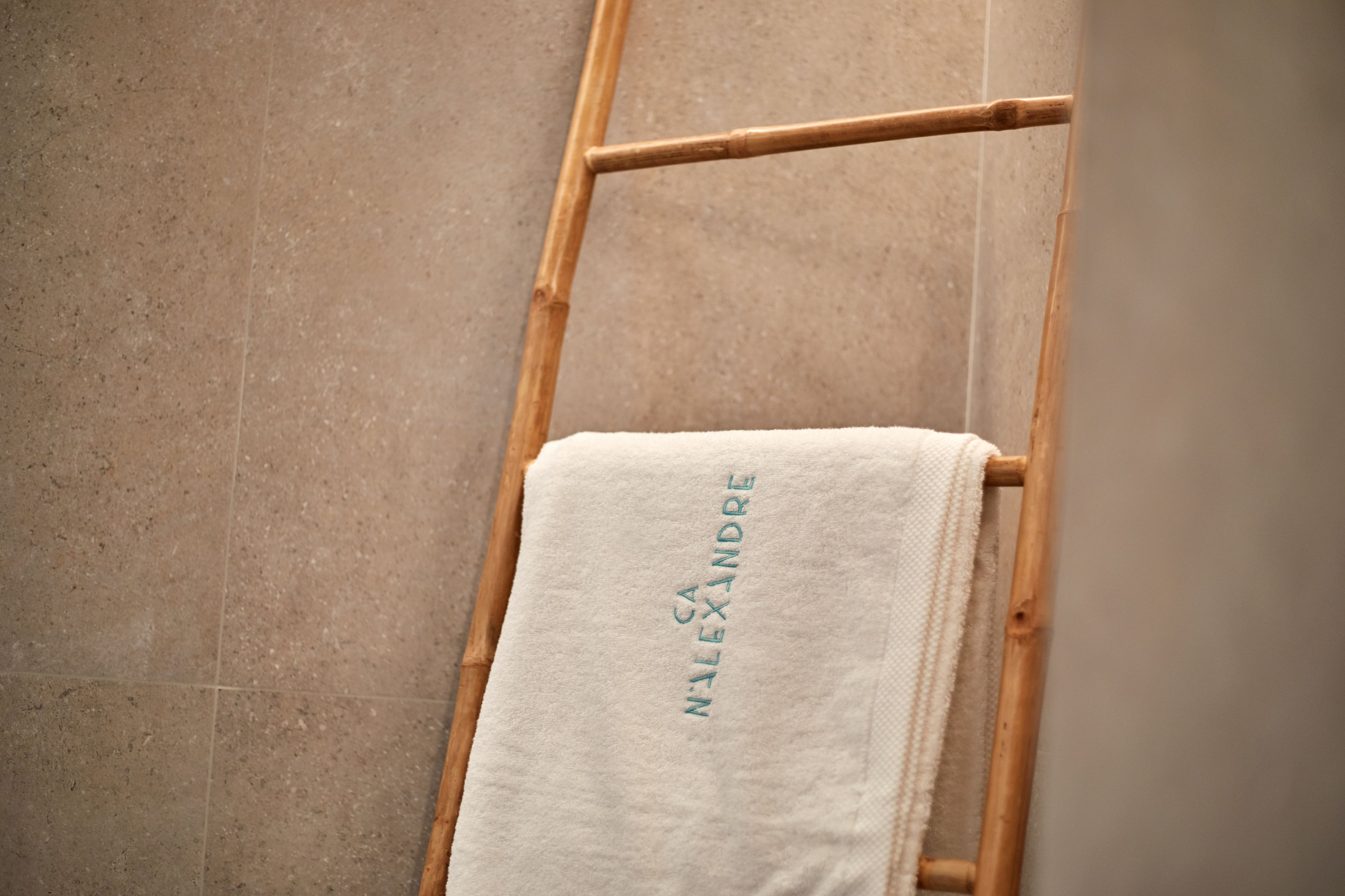 A white towel with embroidered text on a wooden rack.