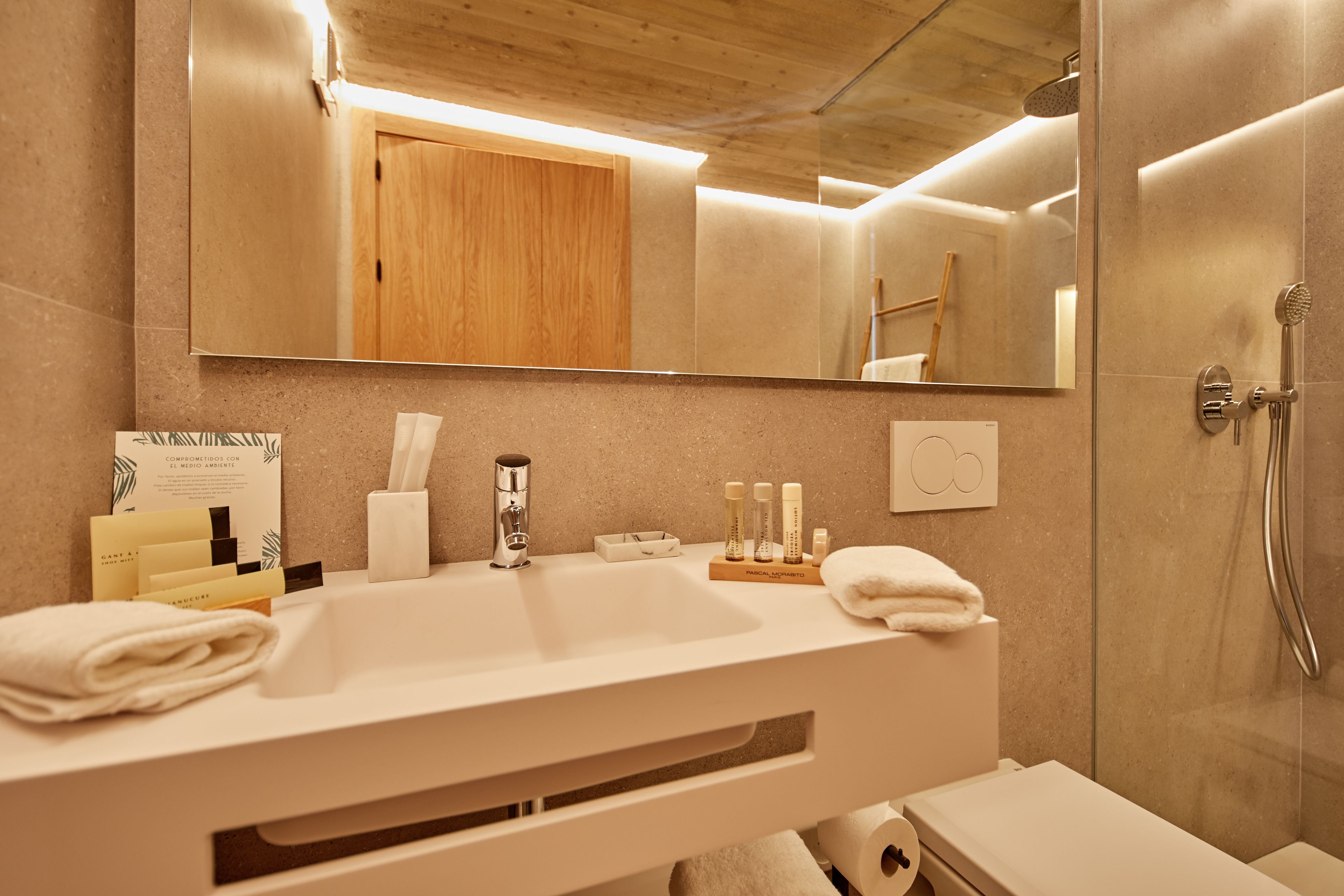 A modern bathroom with a large mirror, a sink, and a shower.