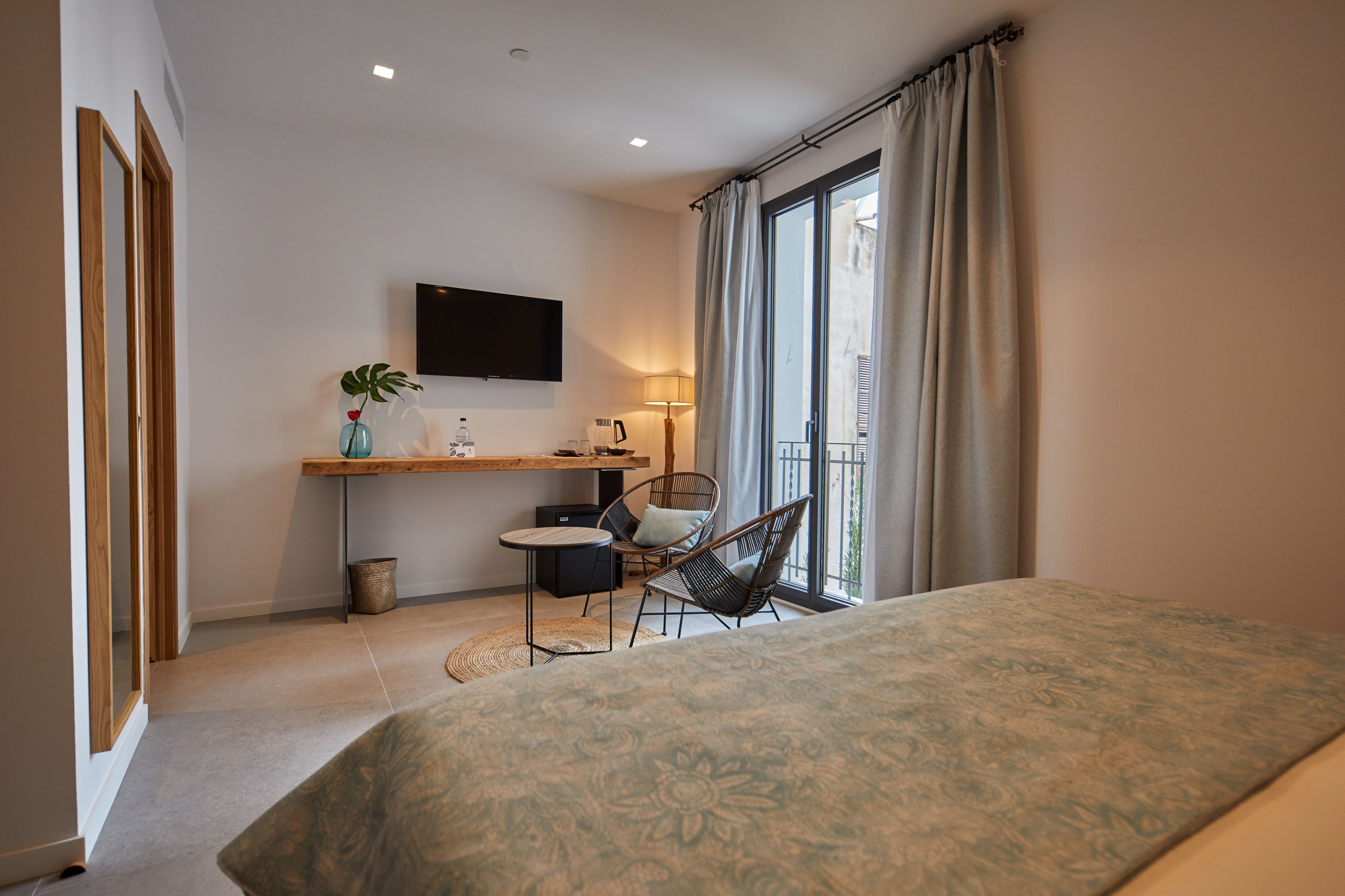 Une chambre à coucher avec un lit, un bureau avec une chaise, une télévision et une fenêtre avec des rideaux.