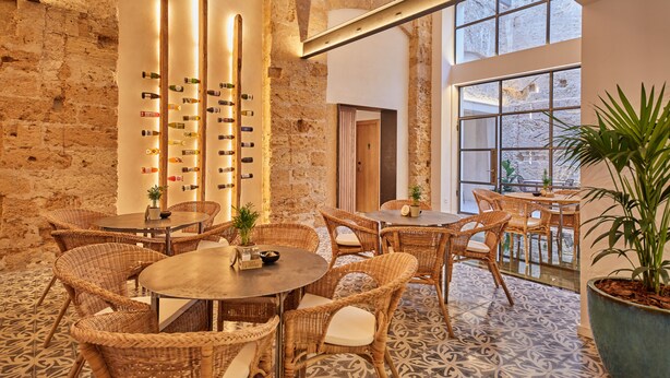 Ein Restaurant mit Korbmöbeln, einer Weinkiste und großen Fenstern.