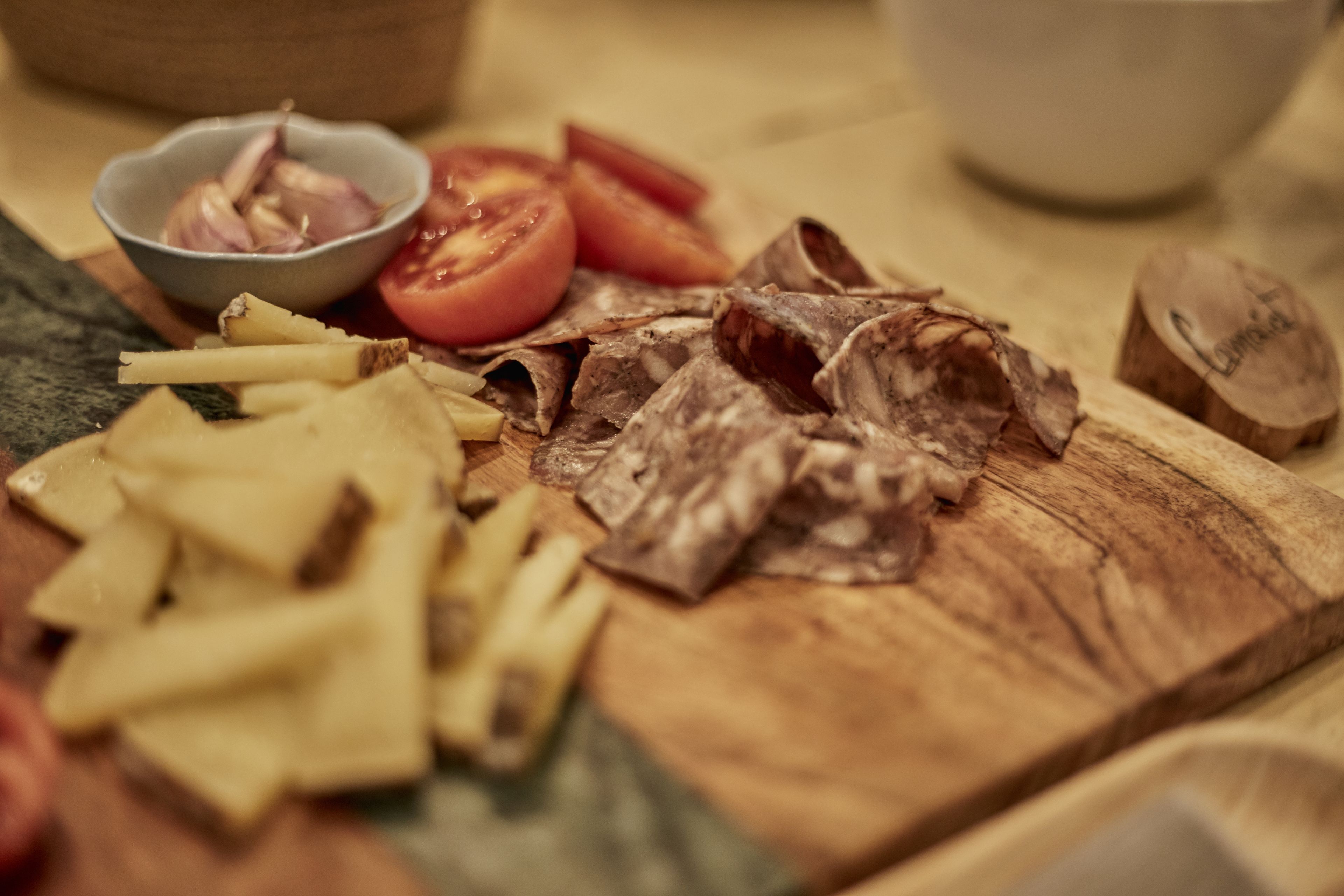 A wooden cutting board with sliced tomatoes, onions, and cheese.