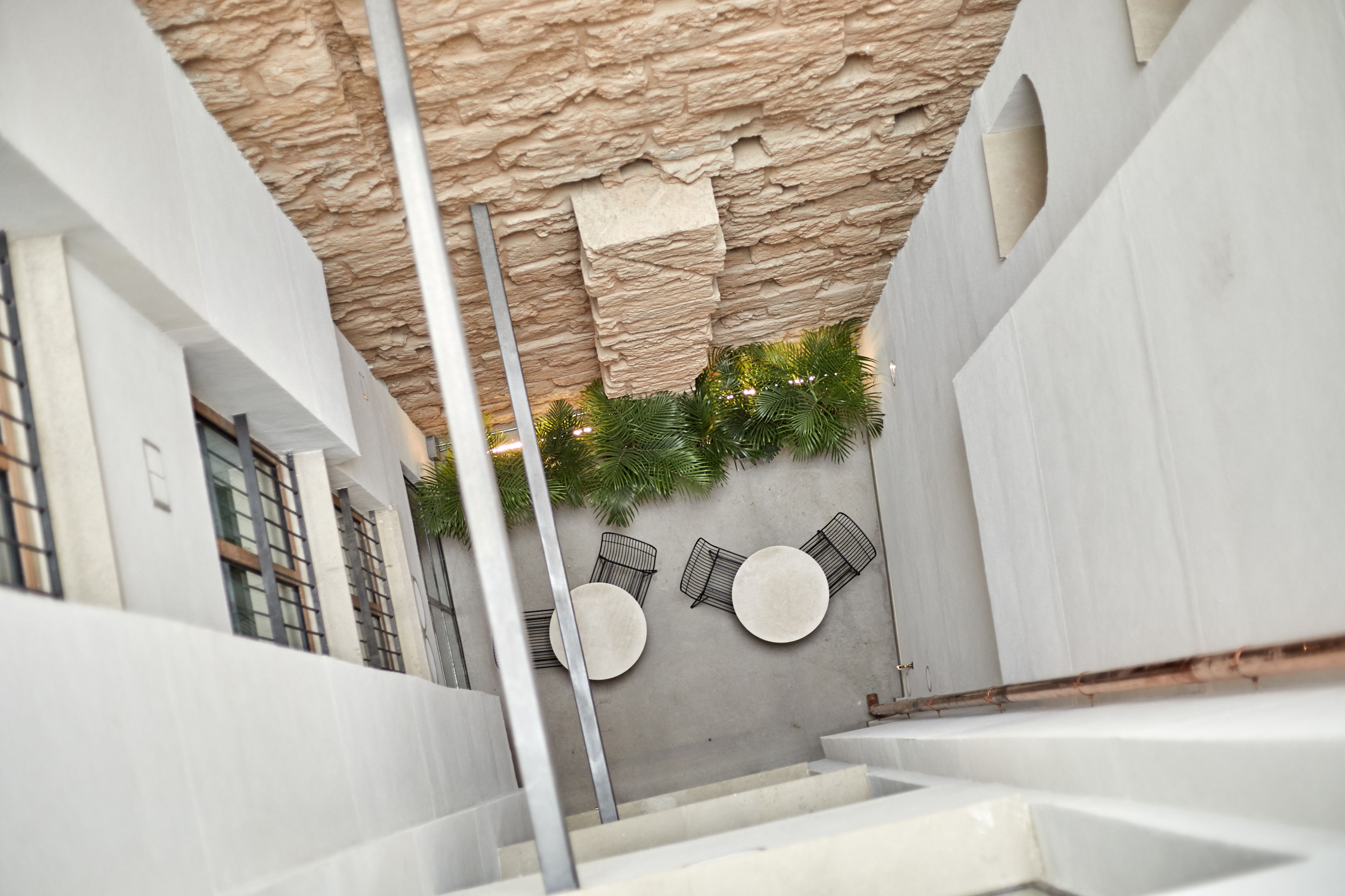 Un intérieur moderne avec un plafond à l’aspect pierre, des murs blancs et un escalier menant à l’étage supérieur.