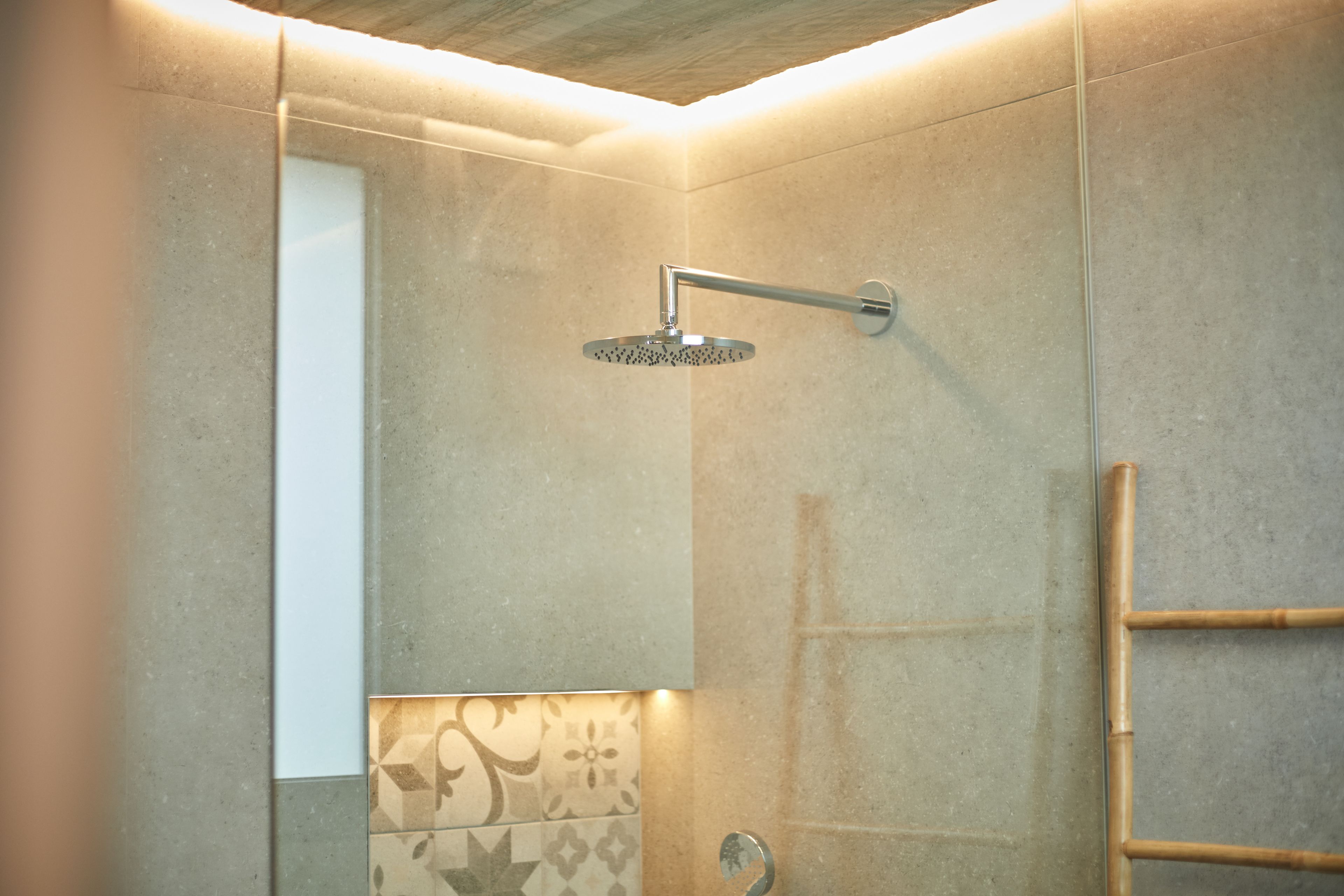 A modern bathroom with a shower, tiled walls, and a wooden ceiling.