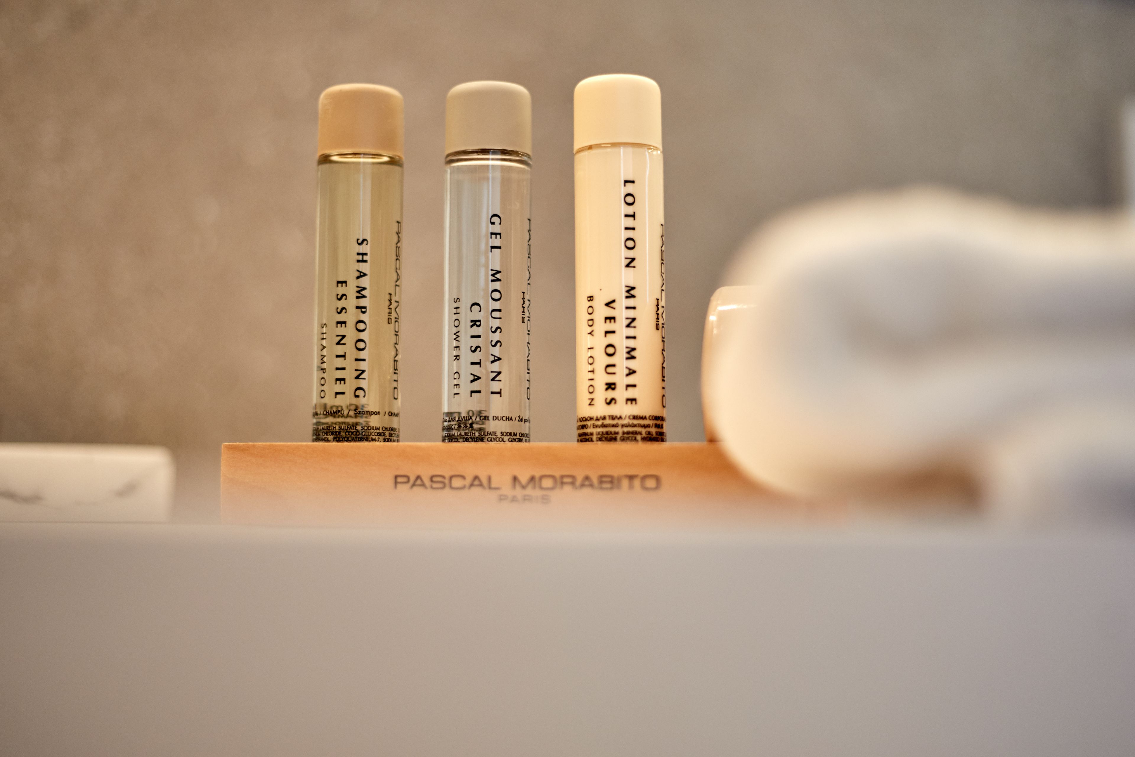 Three bottles of shampoo and lotion on a wooden stand.