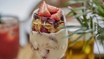 A dessert in a glass with strawberries and granola.
