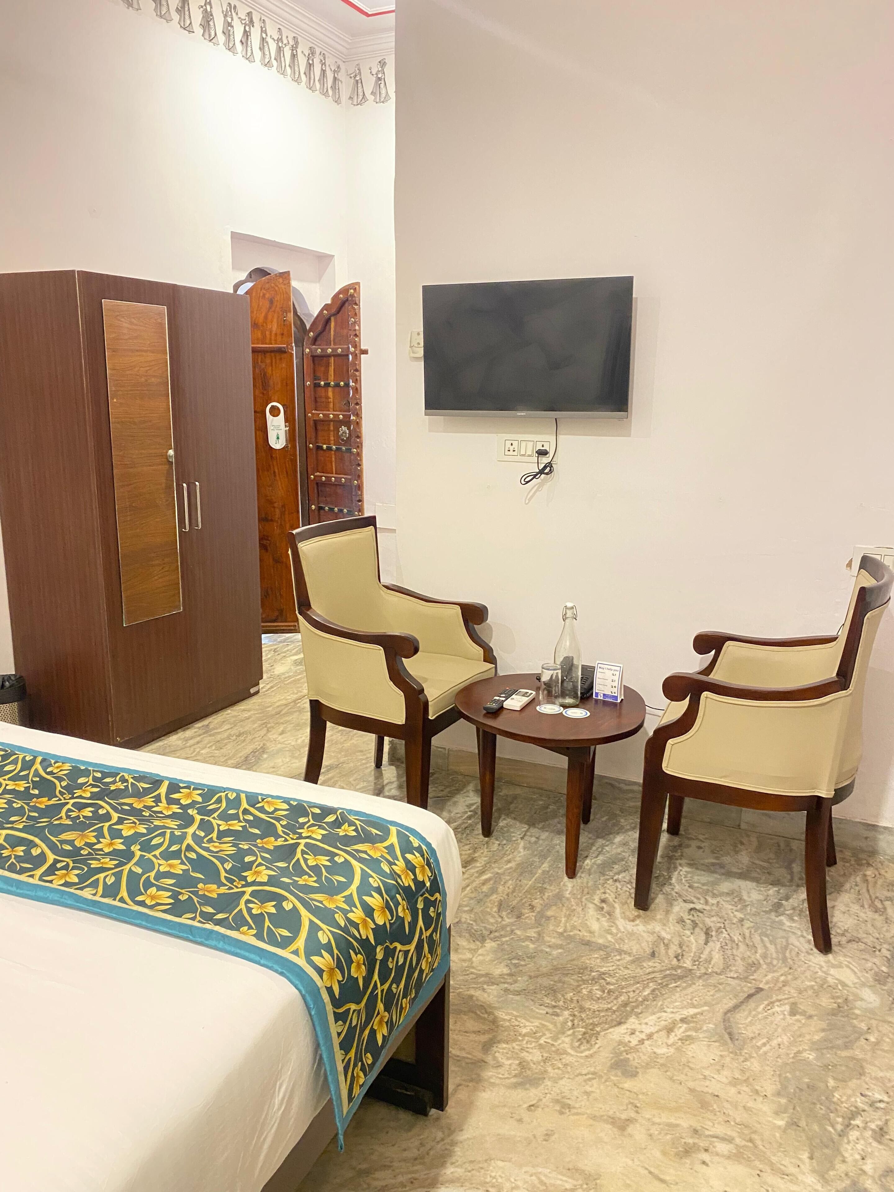Habitación de hotel con cama, dos sillones, una mesita, televisión y armario.