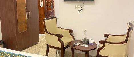 Habitación de hotel con cama, dos sillones, una mesita, televisión y armario.