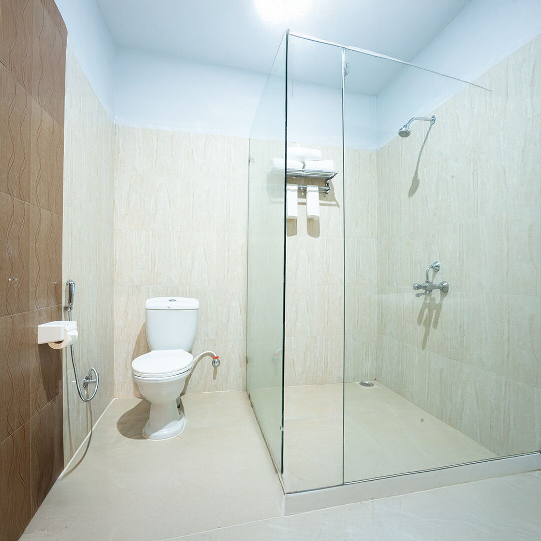 Une salle de bain avec une douche à parois de verre, des toilettes et un porte-serviettes.
