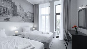 Una habitación de hotel con dos camas, un escritorio y un ventanal con cortinas.