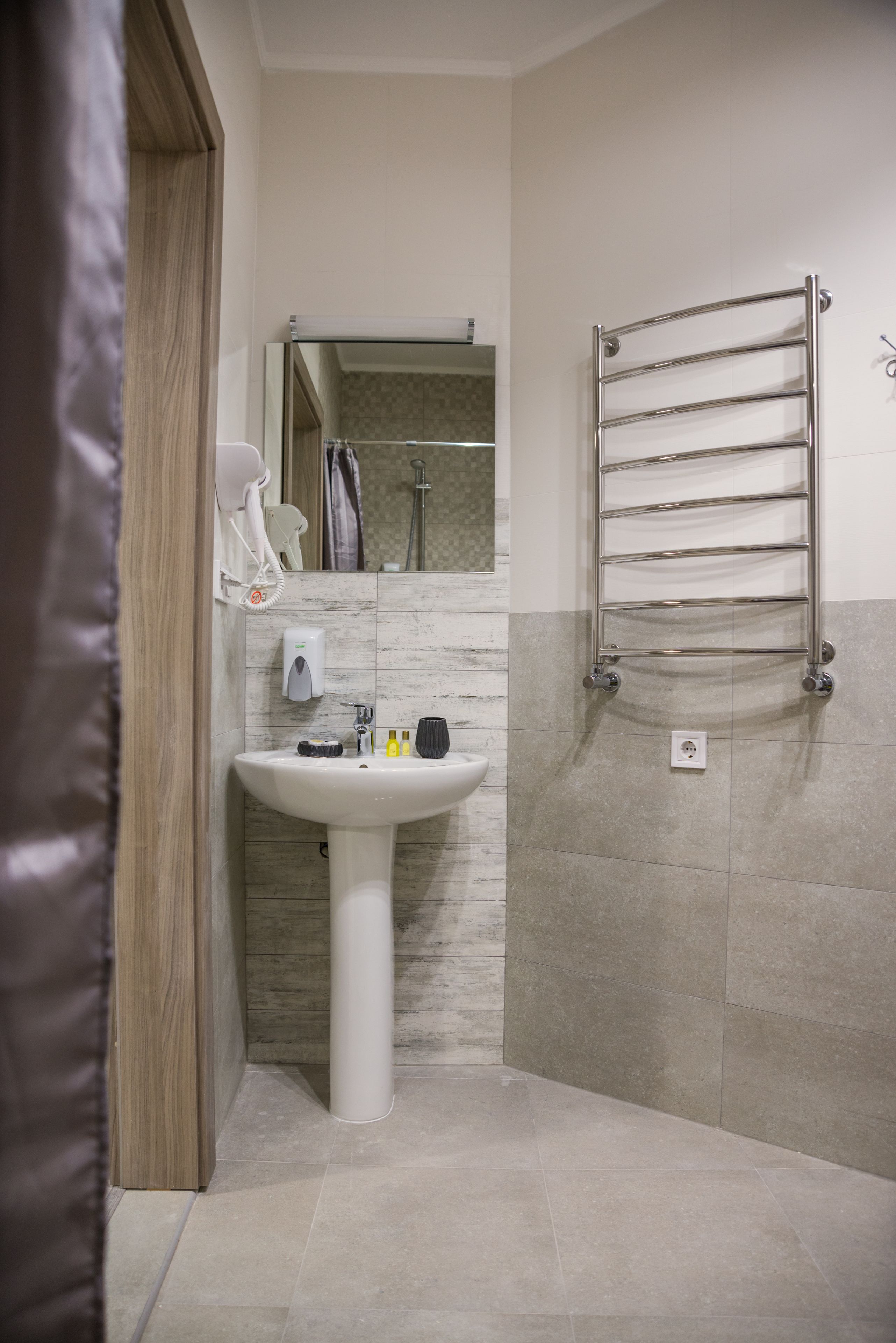 A modern bathroom with a white pedestal sink, a towel rack, and a mirror above the sink.