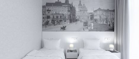 A hotel room with two beds, a cityscape mural on the wall, and a view of the street outside.
