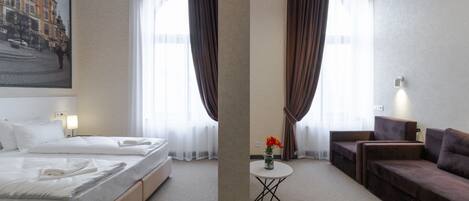 Una habitación de hotel con cama, sofá, una mesita con un florero y un cuadro en la pared.