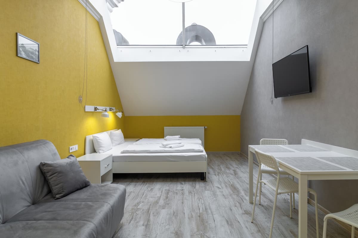 A modern bedroom with a bed, a sofa, a table, and a TV.