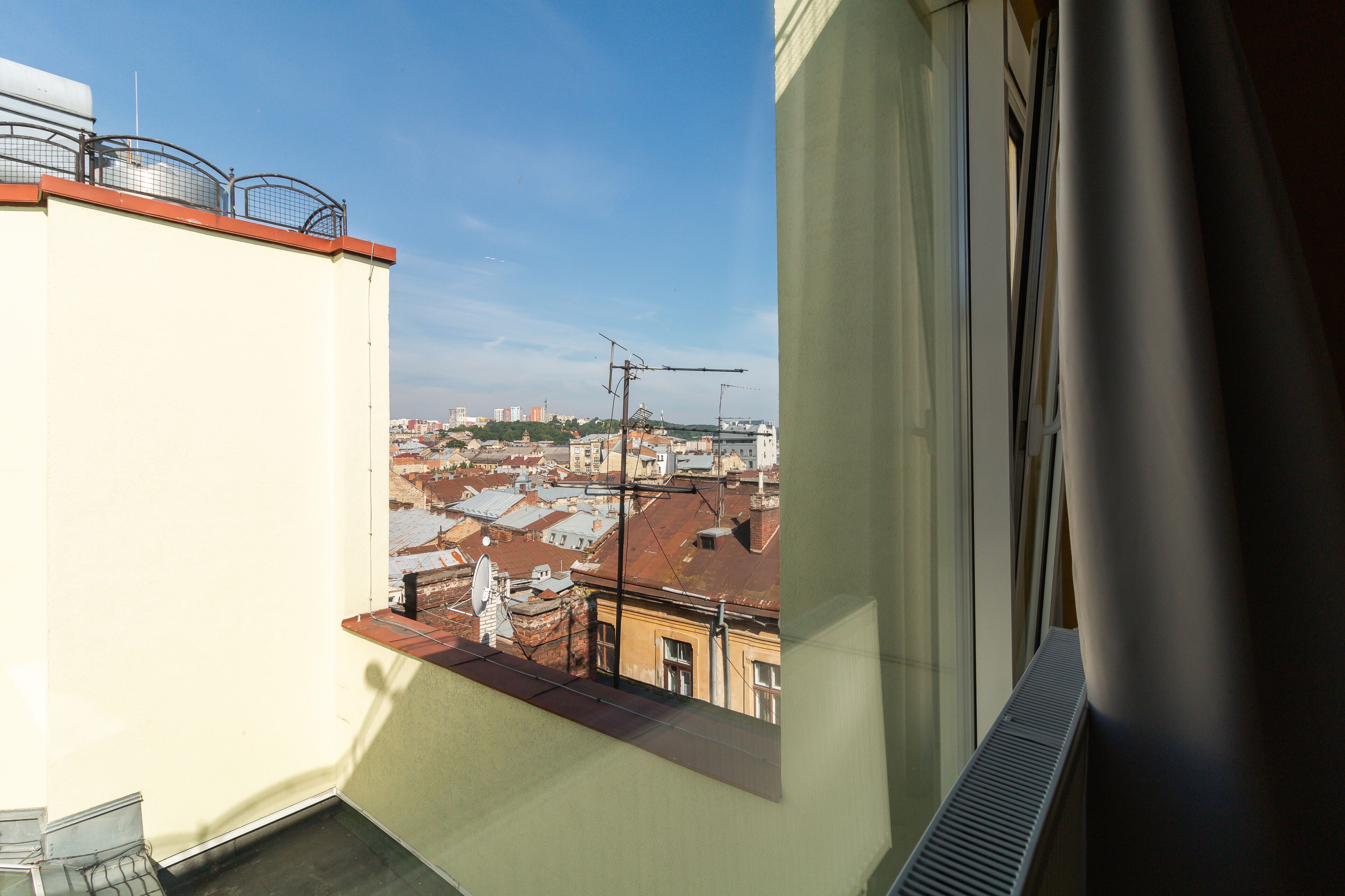 A balcony with a view of a cityscape, including buildings and a clear sky.