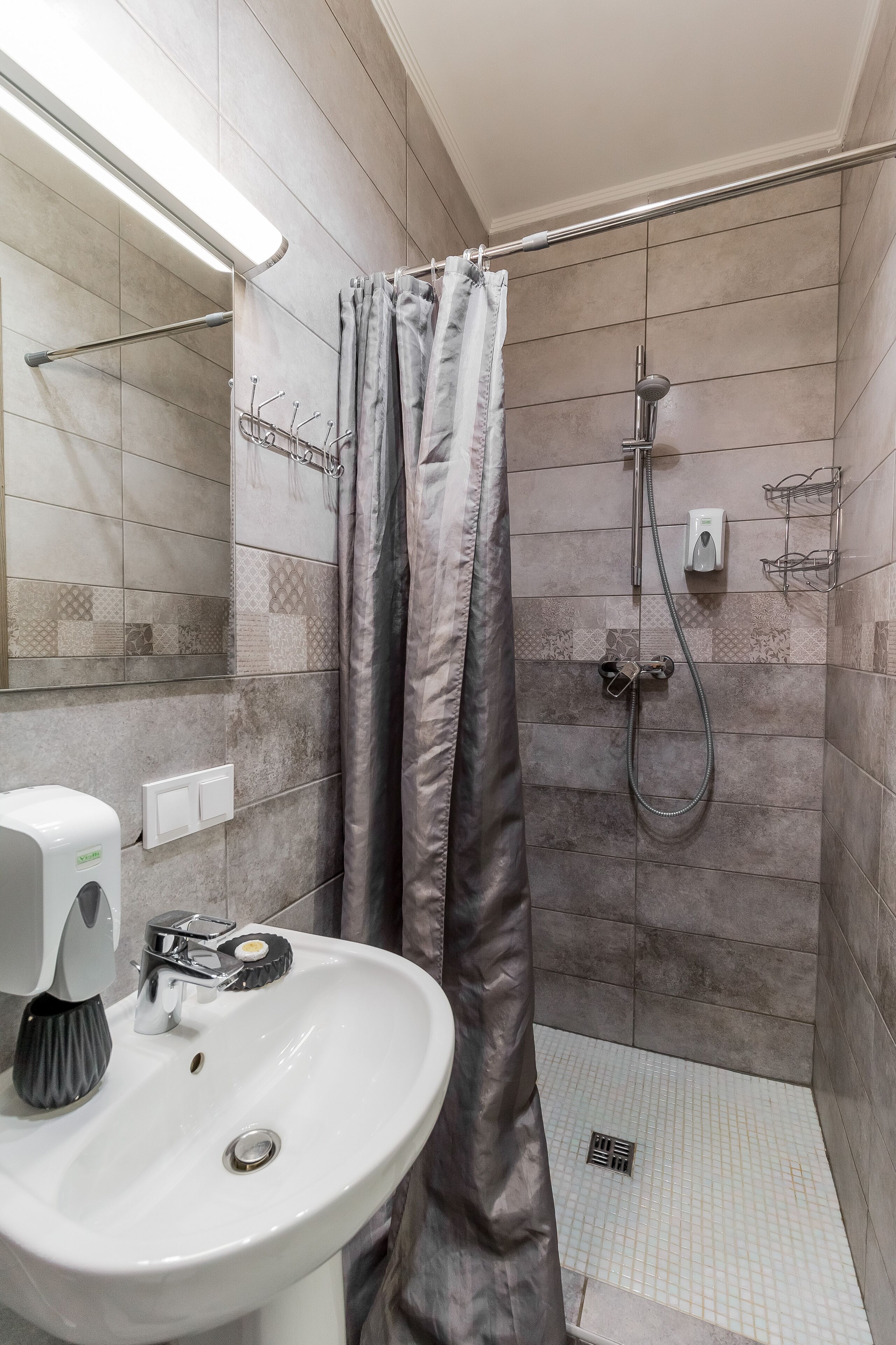 A bathroom with a shower, a sink, and a hand dryer.