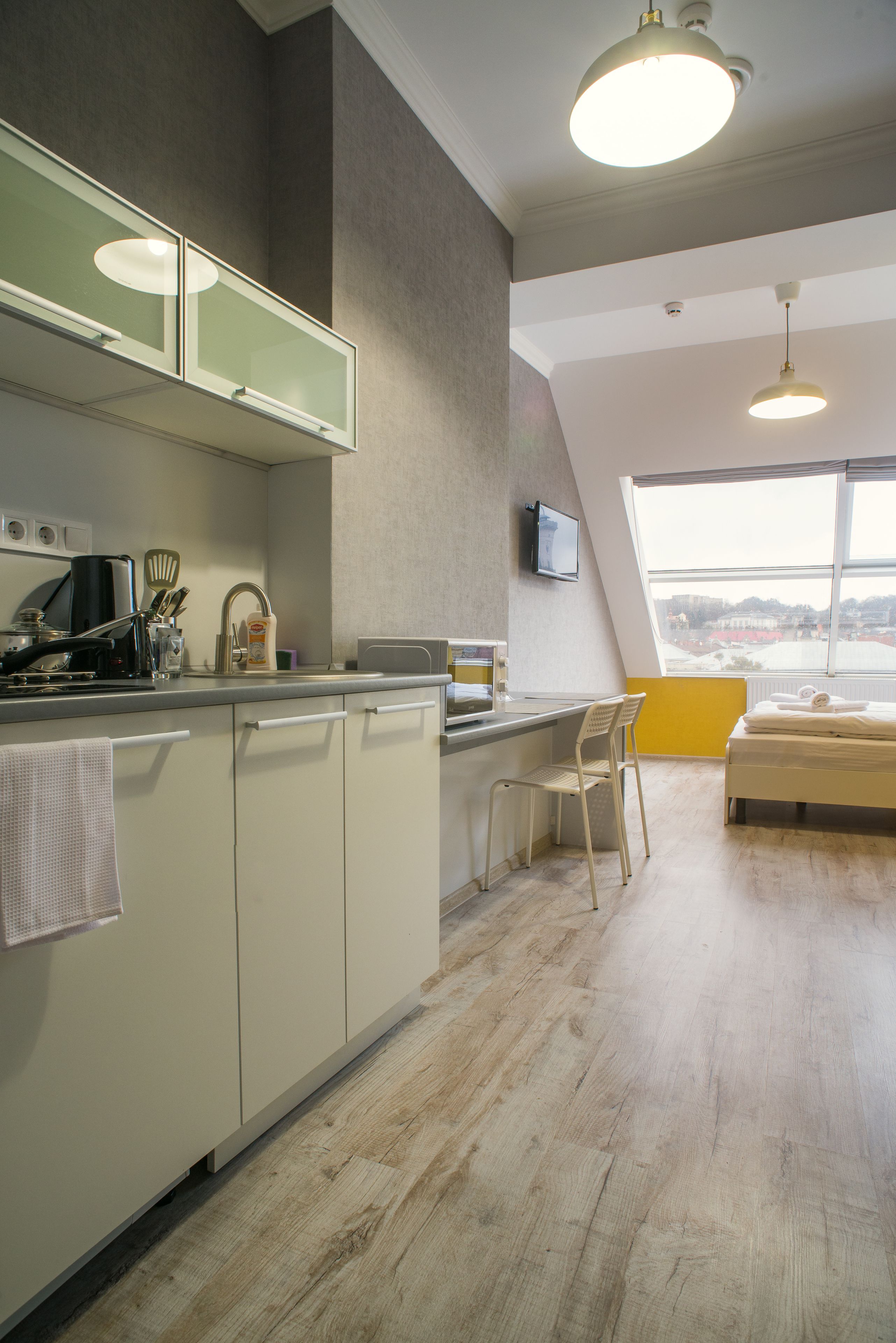 Een moderne keuken met een groot raam, een eethoek met een stoel en een bed in de hoek.
