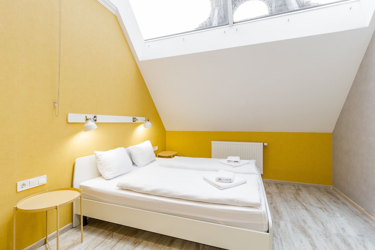 A bedroom with a skylight, a bed, a bedside table, and a radiator.