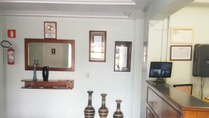 Een receptiezone met een houten toonbank, een flatscreen televisie en drie decoratieve vazen.