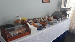 Een buffet met verschillende soorten eten, waaronder brood, gebak en een grill.