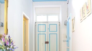 Ein Flur mit einem blauen Schrank, einem Stuhl, einem Blumenstrauß und einem Doppeltürsatz.