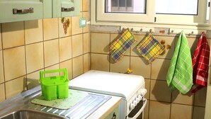 Eine kleine Küche mit grünen Schränken, einem weißen Herd und einem Fenster über der Spüle.