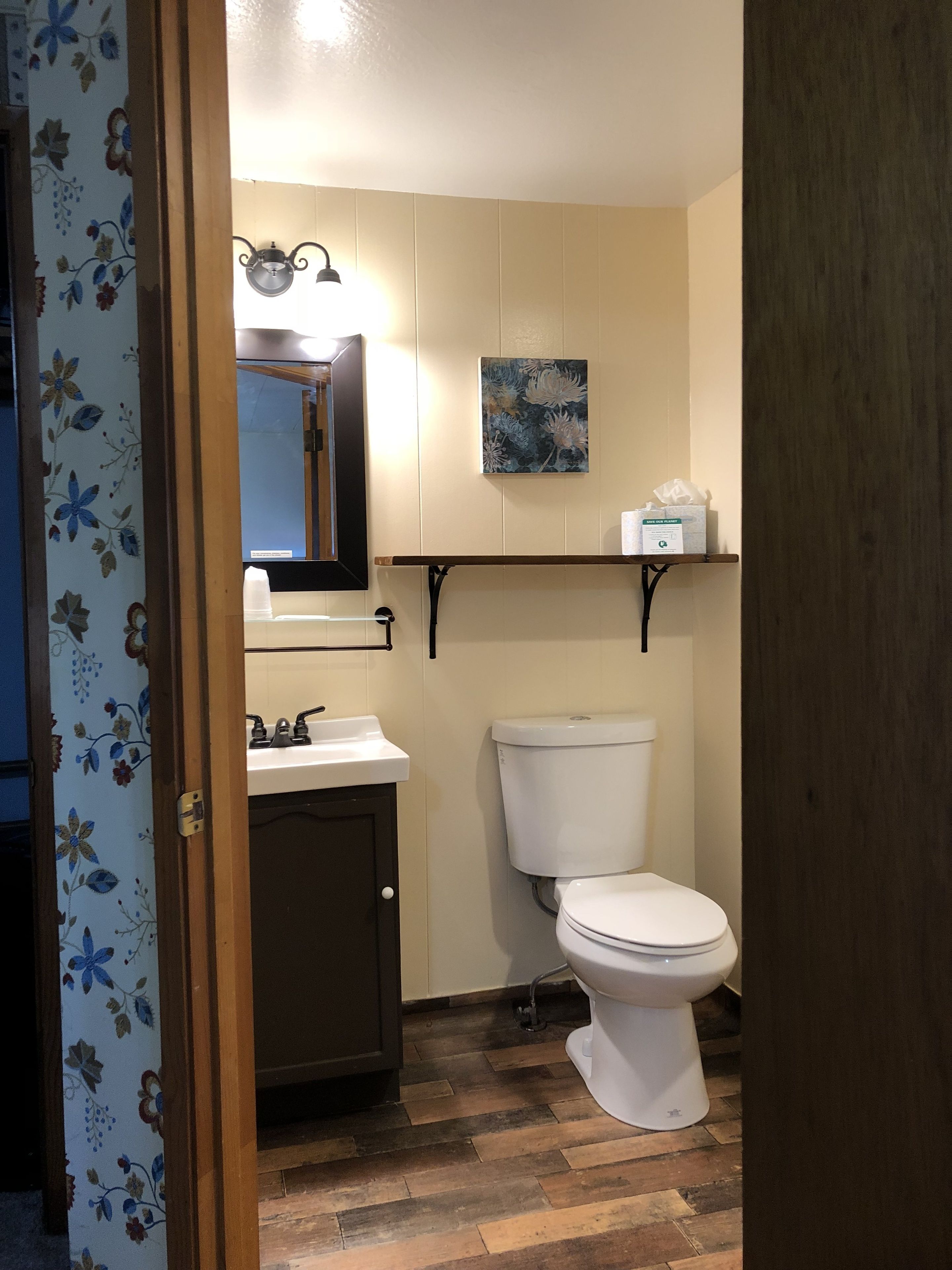 A bathroom with a toilet, sink, and mirror.