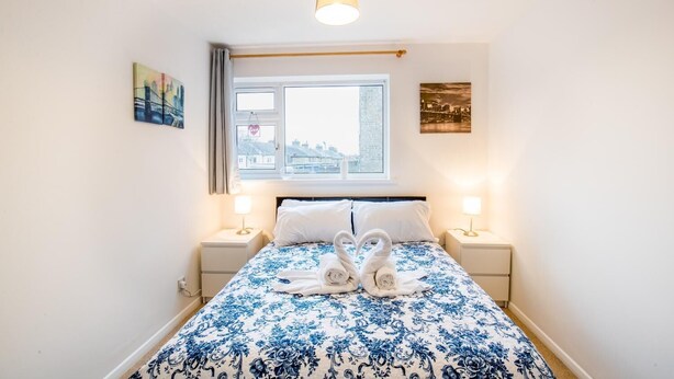 Une chambre à coucher comprenant un lit, deux lampes de chevet, une fenêtre avec vue et deux œuvres d’art accrochées au mur.