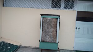 A building with a beige exterior, a green door, and a window with a metal grid. - Hotel Silver Palace - Hostel (New Delhi)