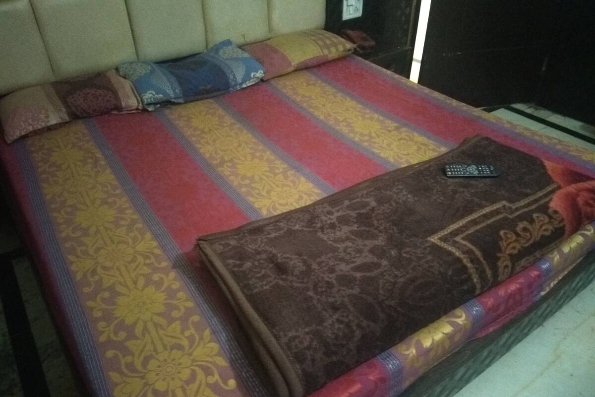 A bed with a striped bedspread and a brown blanket.