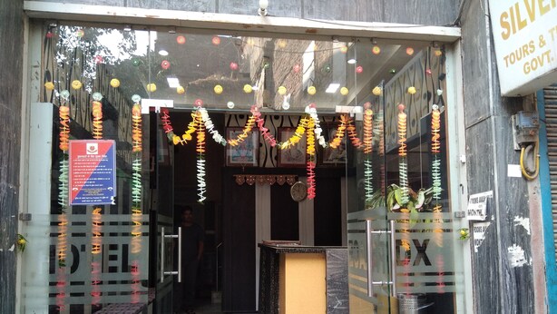 A hotel entrance with a glass door, a reception desk, and a signboard. - Hotel Silver Palace - Hostel (New Delhi)