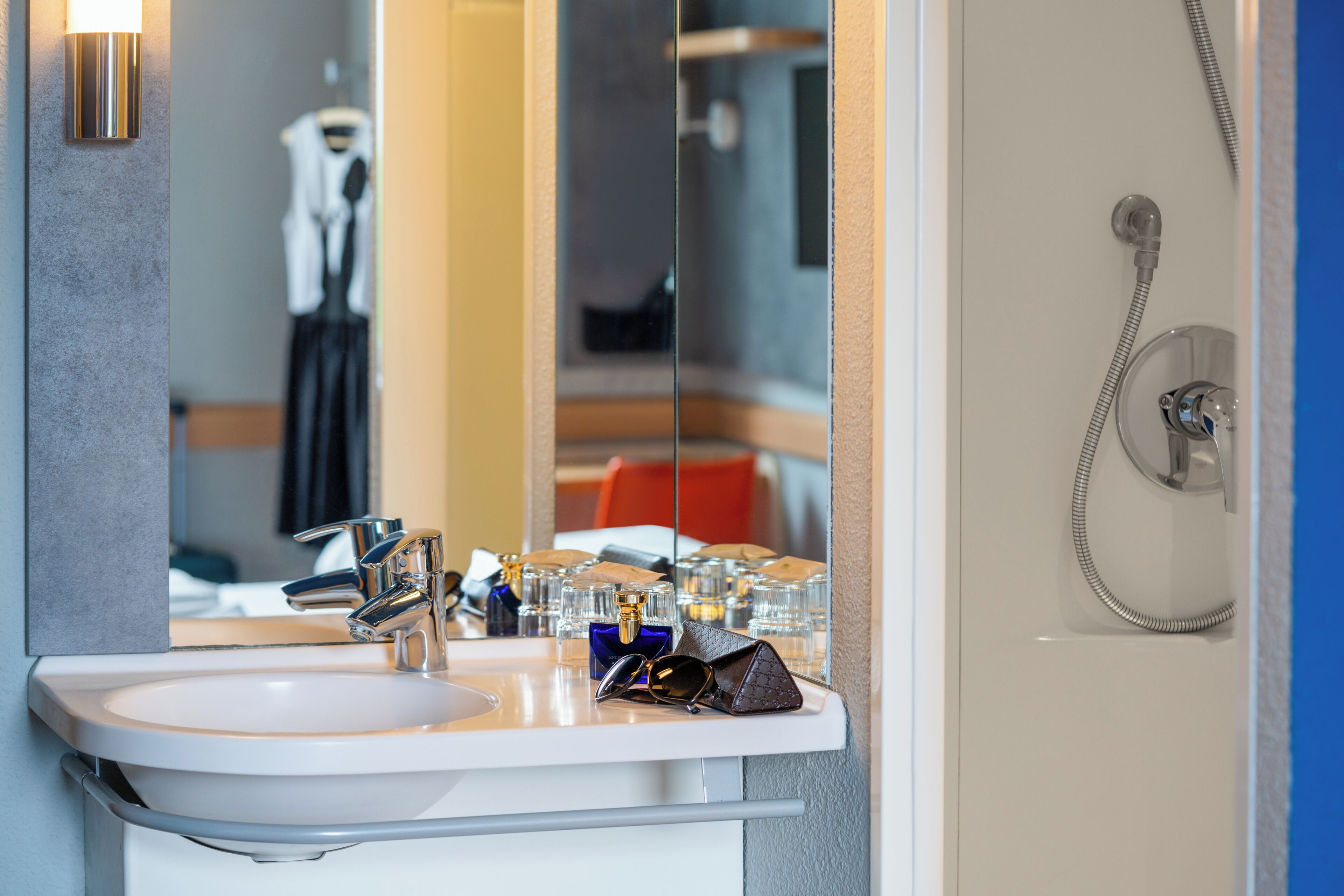 Ein Badezimmer mit einem weißen Waschbecken, einem Spiegel und einer Dusche.