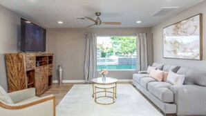 A spacious living room with a grey sofa, a white armchair, a coffee table, and a wooden cabinet. - Modern Living, A Fav! Firepit, BBQ, Min to Airport (Phoenix)