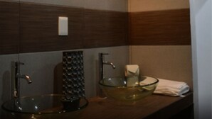 A modern bathroom with two glass sinks, a wooden vanity, and wall-mounted lighting. - Hotel Apartamentos Stone (Bacalar)